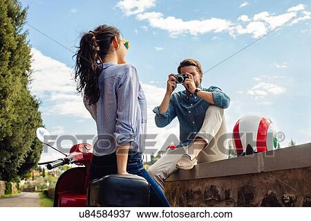 Stock Photo - Young man photographing girlfriend from wall, Florence, Italy. Fotosearch