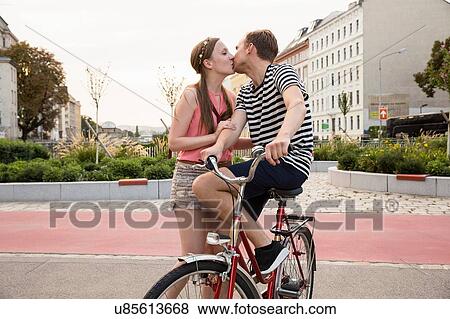 Young man sitting on bicycle kissing young woman View Large Photo Image Stock Photo - Young man sitting on bicycle kissing young woman. Fotosearch