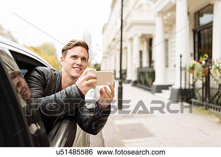 Young man taking photographs from car window, London, England, UK View Large Photo Image Stock Photograph - Young man taking photographs from car window, London, England, UK. Fotosearch