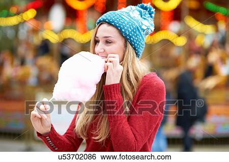 Young woman eating candy floss at funfair, outdoors View Large Photo Image Stock Photograph - Young woman eating candy floss at funfair, outdoors. Fotosearch