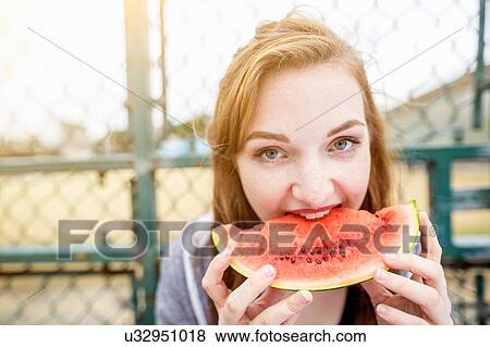 Young woman eating watermelon beside sports ground, London, UK View Large Photo Image Stock Photo - Young woman eating watermelon beside sports ground, London, UK. Fotosearch