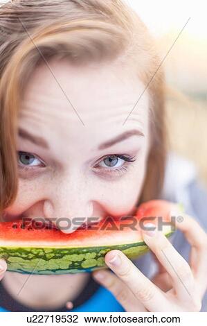 Stock Image - Young woman eating watermelon. Fotosearch
