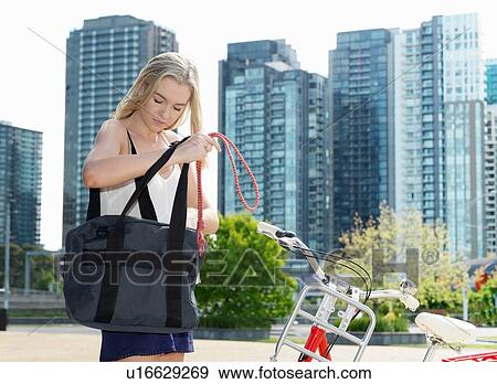 Stock Photo - Young woman looking into bag, Southbank, Melbourne, Australia. Fotosearch