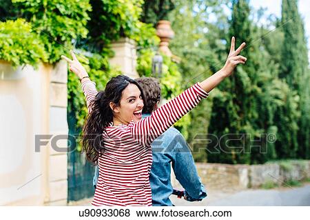 Young woman making peace sign looking over her shoulder from moped, Florence, Italy View Large Photo Image Stock Photo - Young woman making peace sign looking over her shoulder from moped, Florence, Italy. Fotosearch