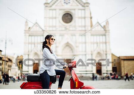 Stock Photograph - Young woman on moped in front of Basilica di Santa Croce, Florence, Italy. Fotosearch