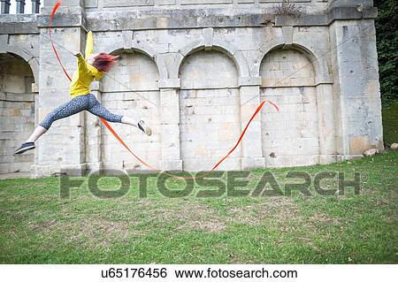 Young woman practising ribbon dance, walled arches in background View Large Photo Image Stock Photograph - Young woman practising ribbon dance, walled arches in background. Fotosearch