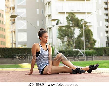 Stock Image - Young woman sitting in park. Fotosearch