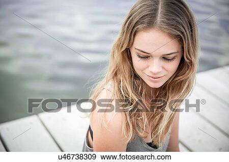 Young woman sitting on jetty, looking away View Large Photo Image Stock Photo - Young woman sitting on jetty, looking away. Fotosearch