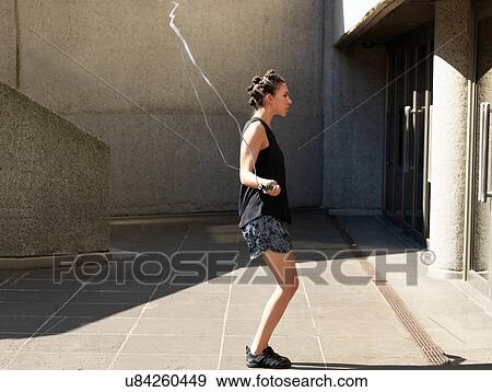 Young woman skipping beside building View Large Photo Image Stock Photo - Young woman skipping beside building. Fotosearch