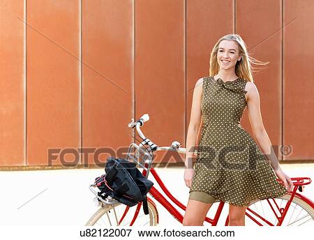 Young woman standing beside bicycle View Large Photo Image Stock Photo - Young woman standing beside bicycle. Fotosearch