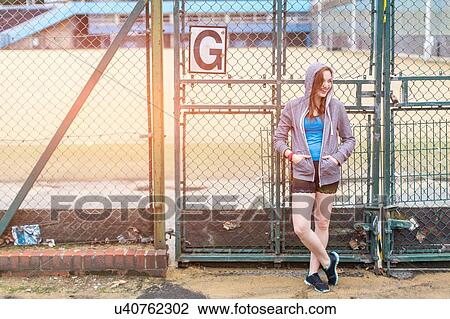 Young woman standing beside sports ground, London, UK View Large Photo Image Stock Image - Young woman standing beside sports ground, London, UK. Fotosearch
