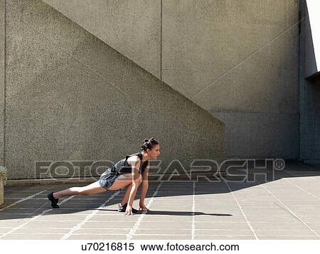 Stock Photography - Young woman stretching in front of concrete wall. Fotosearch