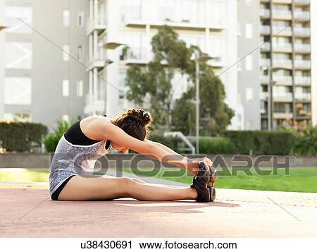 Young woman stretching in park View Large Photo Image Stock Image - Young woman stretching in park. Fotosearch