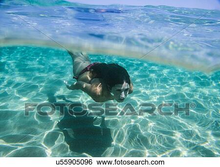 Stock Photograph - Young woman swimming underwater in ocean. Fotosearch