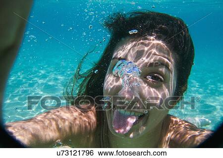 Stock Photograph - Young woman swimming underwater in ocean. Fotosearch