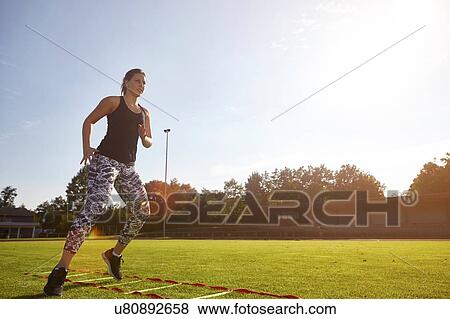 Young woman training on agility ladder on grass View Large Photo Image Stock Photo - Young woman training on agility ladder on grass. Fotosearch