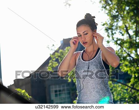 Young woman using earphones View Large Photo Image Stock Photo - Young woman using earphones. Fotosearch