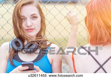 Young woman using smartphone beside fence View Large Photo Image Stock Photography - Young woman using smartphone beside fence. Fotosearch