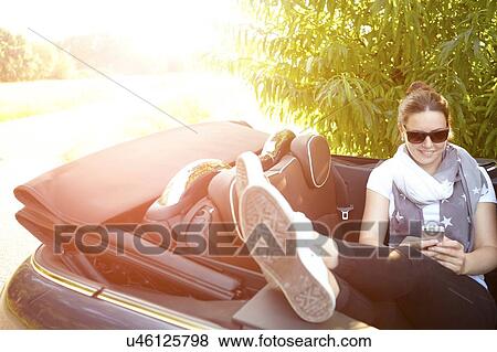 Young woman with feet up in convertible back seat View Large Photo Image Stock Photo - Young woman with feet up in convertible back seat. Fotosearch