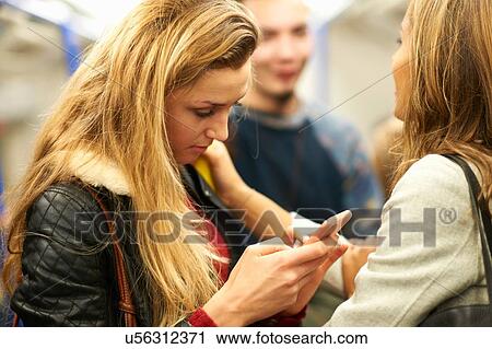 Young woman with friends reading taking smartphone texts on London underground train, London, UK View Large Photo Image Stock Image - Young woman with friends reading taking smartphone texts on London underground train, London, UK. Fotosearch