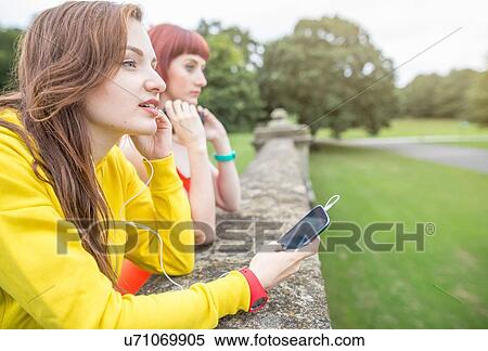 Young woman with smartphone leaning against stone wall View Large Photo Image Stock Photography - Young woman with smartphone leaning against stone wall. Fotosearch