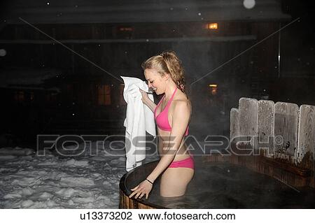 Stock Image - Young woman with towel standing in hot tub. Fotosearch