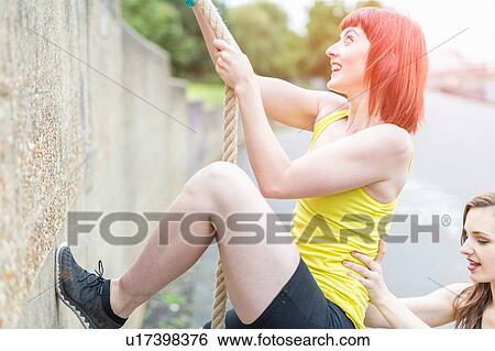 Young women climbing over wall with rope View Large Photo Image Stock Photograph - Young women climbing over wall with rope. Fotosearch