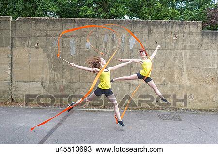Stock Image - Young women practising ribbon dance on court. Fotosearch