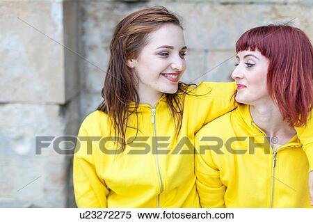 Stock Photography - Young women smiling, stone wall in background. Fotosearch