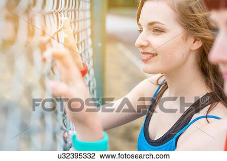 Stock Image - Young women standing beside fence. Fotosearch
