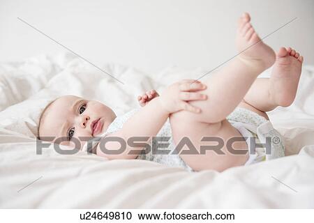 Baby girl (12-17 months) lying down on bed View Large Photo Image Stock Image - Baby girl (12-17 months) lying down on bed. Fotosearch