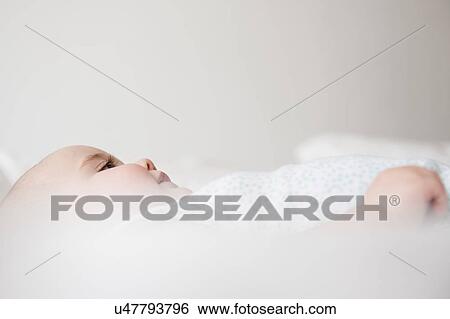Baby girl (12-17 months) lying down on bed View Large Photo Image Stock Photograph - Baby girl (12-17 months) lying down on bed. Fotosearch