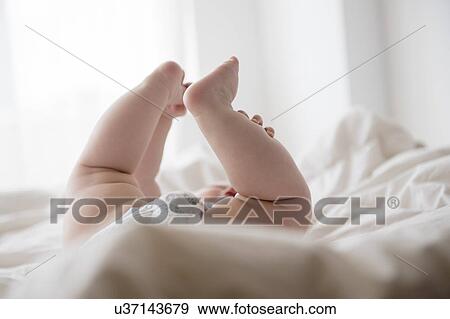 Stock Photo - Baby girl (12-17 months) lying down with legs up. Fotosearch