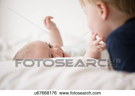 Baby girl (12-17 months) touching brother face (2-3) View Large Photo Image Stock Photograph - Baby girl (12-17 months) touching brother face (2-3). Fotosearch