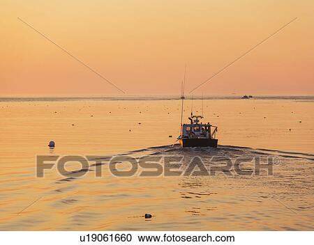 Stock Image - Boat on sea at sunrise. Fotosearch