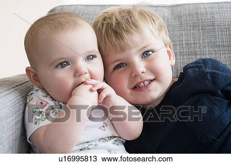 Boy (2-3) with baby sister (12-17 months) sitting on sofa View Large Photo Image Stock Image - Boy (2-3) with baby sister (12-17 months) sitting on sofa. Fotosearch