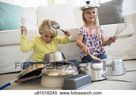 Stock Photography - Boy (4-5) and girl (6-7) playing on pots on living room. Fotosearch