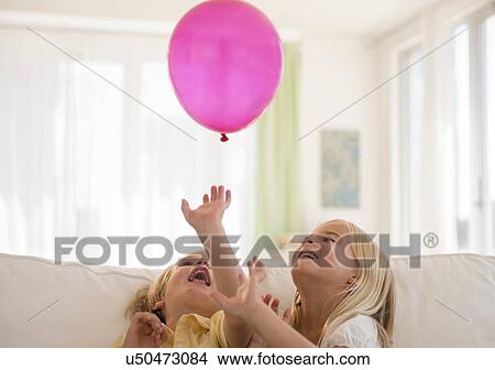 Boy (4-5) and girl (6-7) playing with pink balloon View Large Photo Image Picture - Boy (4-5) and girl (6-7) playing with pink balloon. Fotosearch