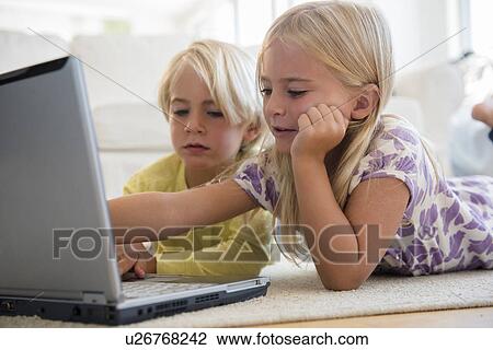 Stock Image - Boy (4-5) and girl (6-7) using laptop. Fotosearch