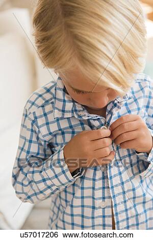 Stock Photograph - Boy (4-5) buttoning shirt. Fotosearch