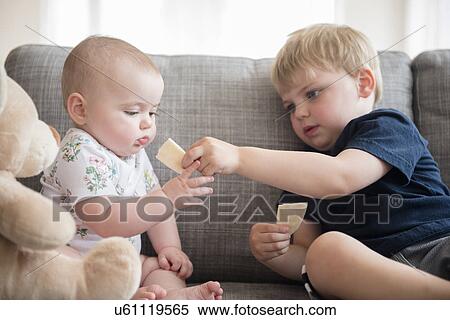 Brother (2-3) sharing crackers with baby sister (12-17 months) View Large Photo Image Stock Photography - Brother (2-3) sharing crackers with baby sister (12-17 months). Fotosearch