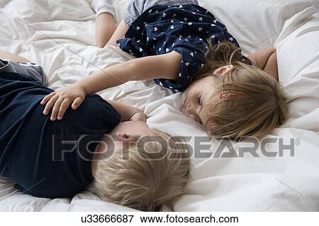 Stock Photo - Brother (2-3) with sister (2-3) sleeping on bed. Fotosearch