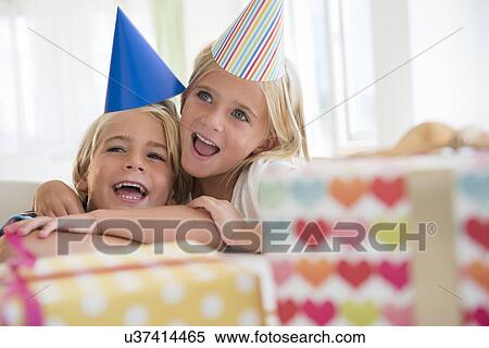 Stock Photography - Brother (4-5) and sister (6-7) in embrace at birthday party. Fotosearch