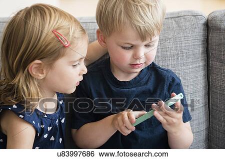Brother with sister (2-3) playing with smart phone View Large Photo Image Stock Photograph - Brother with sister (2-3) playing with smart phone. Fotosearch