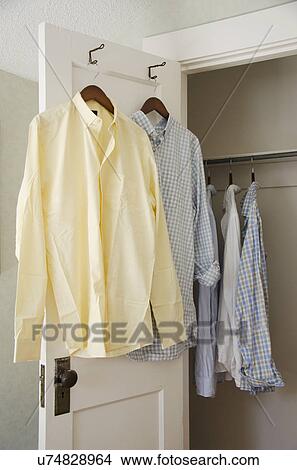Picture - Button down shirts hanging on cloth hangers. Fotosearch
