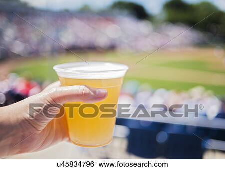 Close-up of hand holding beer at stadium View Large Photo Image Stock Photograph - Close-up of hand holding beer at stadium. Fotosearch