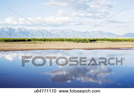 Clouds reflecting in lake with mountains in background View Large Photo Image Stock Image - Clouds reflecting in lake with mountains in background. Fotosearch