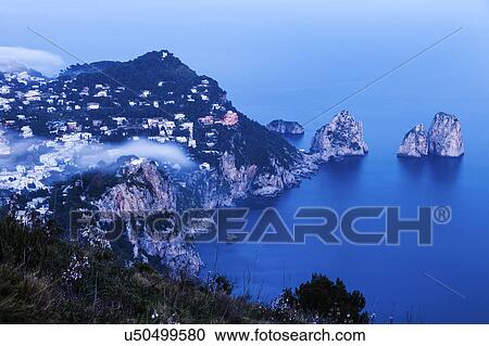 Coastal town and Faraglioni at sunset View Large Photo Image Stock Image - Coastal town and Faraglioni at sunset. Fotosearch