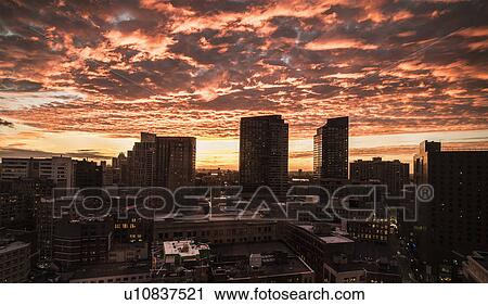 Stock Image - Dramatic sky over city at sunset. Fotosearch