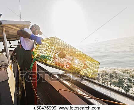 Stock Photo - Fishermen throwing lobster trap. Fotosearch